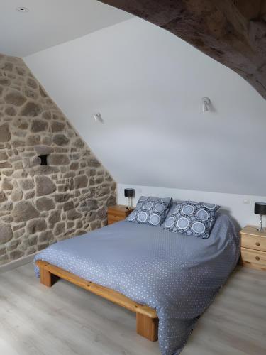 a bed in a room with a stone wall at Le gîte de L'Étable in Magny-le-Désert