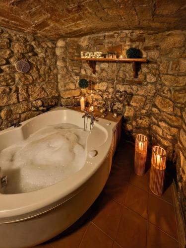 a bath tub in a stone bathroom with candles at Hotel Residence Sant'Uberto in Roccastrada