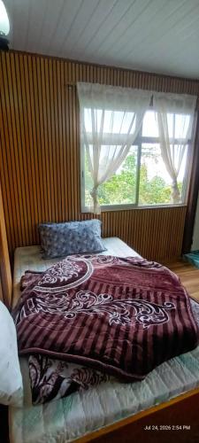 a bed in a bedroom with a large window at Wang Homestay in Sukhia Pokhari