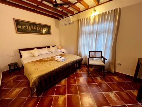 a bedroom with a bed and a chair and a window at Haritham Heritage Villa - Rooms in Vadakkāncheri