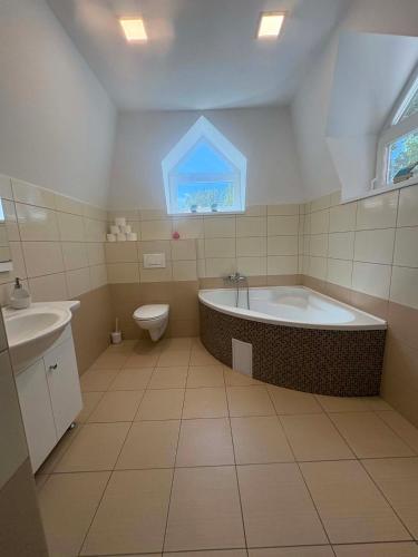 a bathroom with a tub and a toilet and a sink at Balat-ON Apartman in Balatonberény
