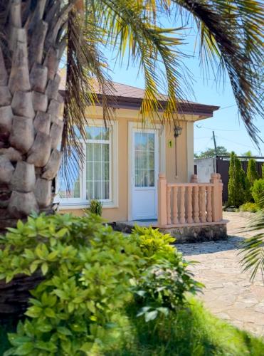 a small yellow house with a palm tree at GRIGOLETI River Club in Grigoleti