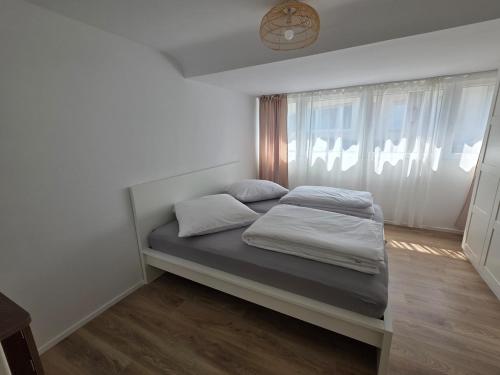 a bed in a white room with a window at Design-Dachgeschosswohnung am Schwarzwald in Pforzheim