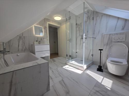 a white bathroom with a tub and a toilet at Design-Dachgeschosswohnung am Schwarzwald in Pforzheim