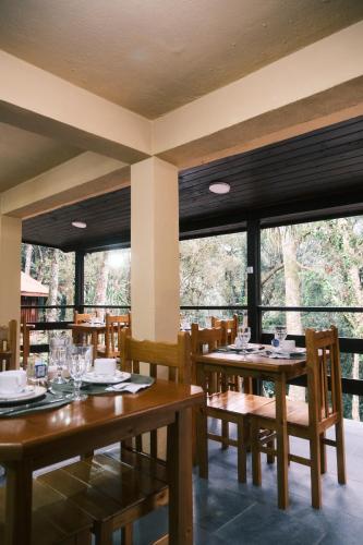 a restaurant with wooden tables and chairs and windows at Villa di Serra by Concavus in Monte Verde