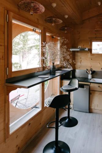 a kitchen with black counter stools and a window at Tiny Isle in L'Isle-sur-la-Sorgue