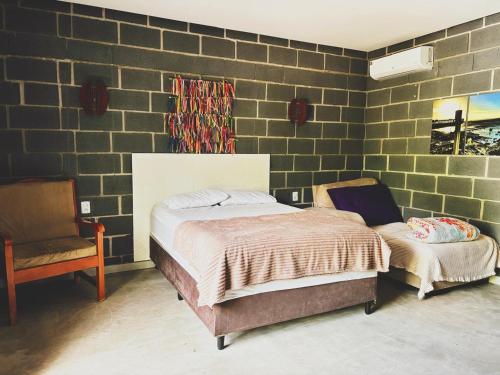 a bedroom with a bed and a chair at Chalés do quintal da chapada in Palmeiras