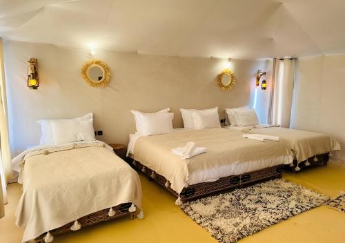 two beds in a room with yellow floors and mirrors at Sahara Nomadic Luxury Camp in Merzouga