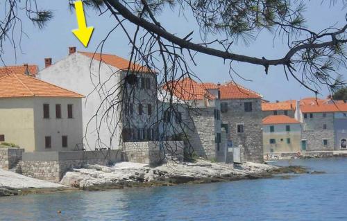 a building with a yellow arrow on it next to the water at Apartments Sova By the Sea in Postira