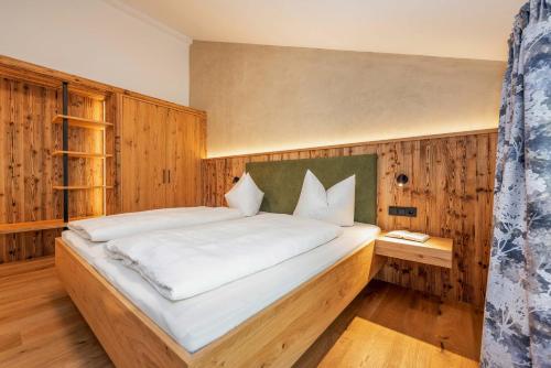 a bedroom with a large bed in a wooden wall at Landhaus Lengg in Reit im Winkl