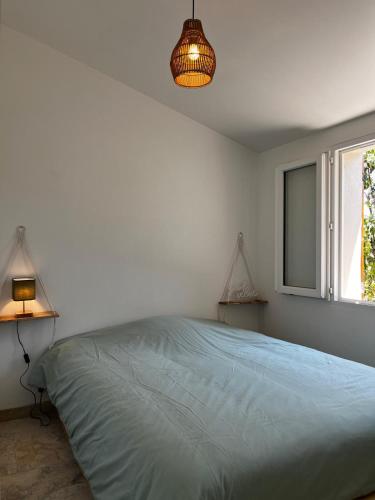a bedroom with a bed and a lamp and a window at Maisonnette et Campagne Provençale, avec Piscine in Orgon