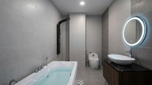 a bathroom with a tub and a sink and a mirror at Mai Song Linh in Phan Rang–Tháp Chàm