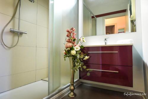 a vase of flowers in a bathroom with a sink at Logis Hôtel Restaurant La Palette in Wettolsheim
