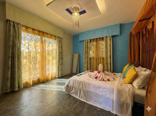 a bedroom with a bed with blue walls and windows at Prestige Majorelle Résidence Prestige Majorelle in Ngaparou