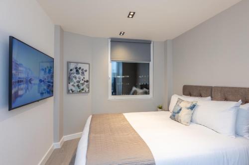 a bedroom with a large white bed with a window at Diff-Rent Studios with gym & Fast Access to Central London & Wembley in Harrow