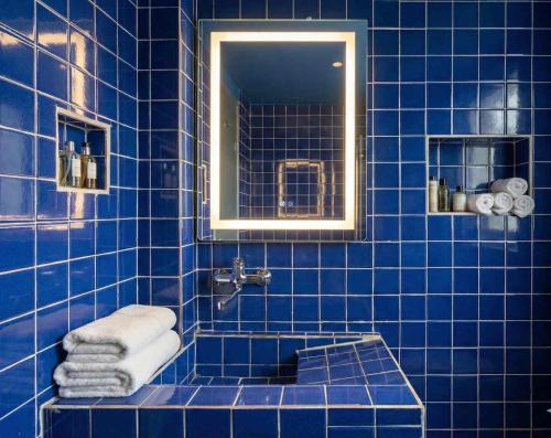 a blue tiled bathroom with a sink and a mirror at Prestige Majorelle Résidence Prestige Majorelle in Ngaparou