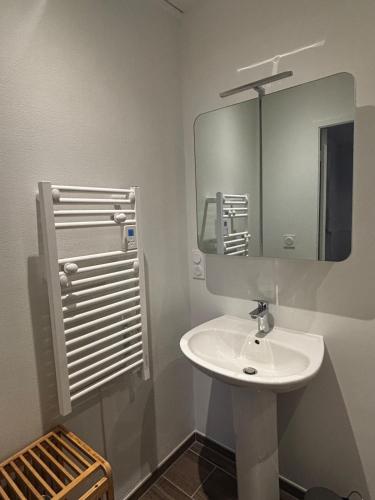 a bathroom with a white sink and a mirror at La Parenthèse Meymacoise in Meymac