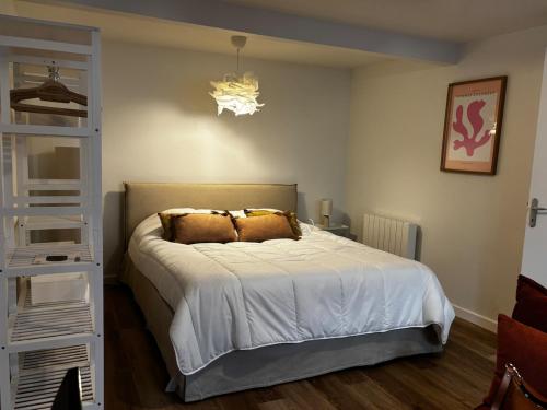 a bedroom with a large bed and a chandelier at La Parenthèse Meymacoise in Meymac