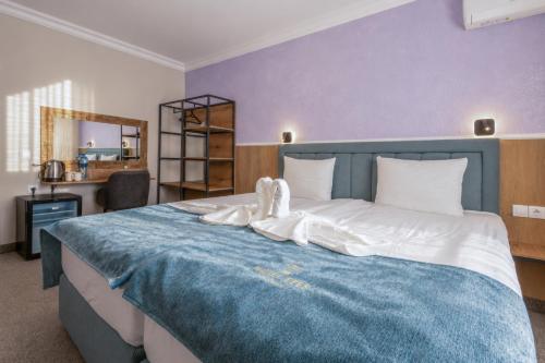 a bedroom with a large blue bed with white sheets at Хотел EFES in Burgas
