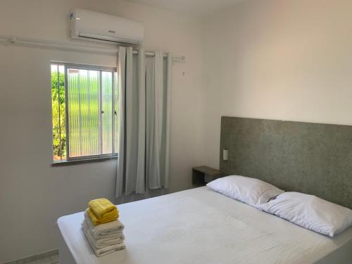a bedroom with a white bed and a window at Fortal Flat in Fortaleza