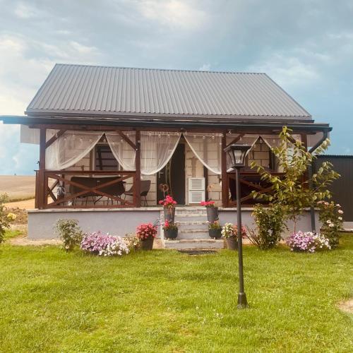 a house with a porch and flowers in the yard at Magia Leśnych Dolin Zwiartów 44, 22-610 Krynice in Zwiartów