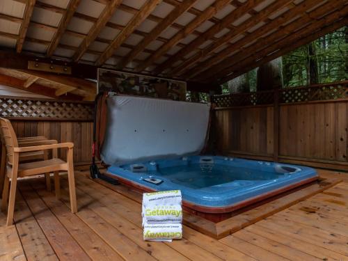 a hot tub on a deck with a table and a chair at Naturbyn Retreat in Glacier
