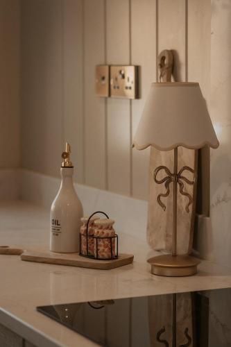 a table with a lamp and a bottle on it at Hathaway Hamlet in Stratford-upon-Avon