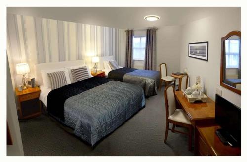 a hotel room with two beds and a desk at Woodfield House Hotel in Limerick