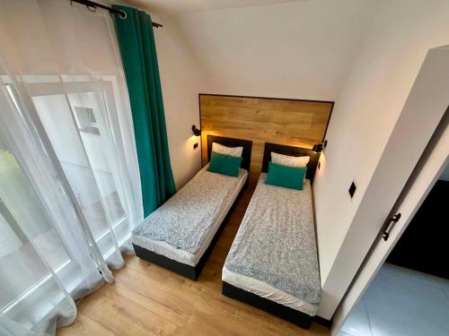 two beds in a small room with green curtains at Apartamenty Chata u Rybaka in Jantar