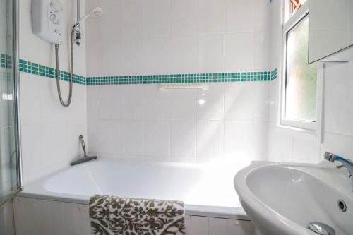 a white bathroom with a tub and a sink at Coombe Lodge No 9 in Bude