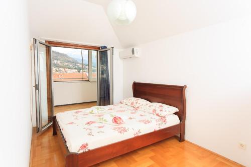 een slaapkamer met een bed en een groot raam bij Apartment DV Magnolia in Tivat