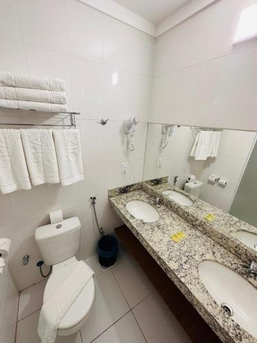 a bathroom with two sinks and a toilet and a mirror at Spazzio diRoma in Caldas Novas