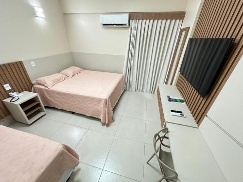 a small room with two beds and a television at Spazzio diRoma in Caldas Novas