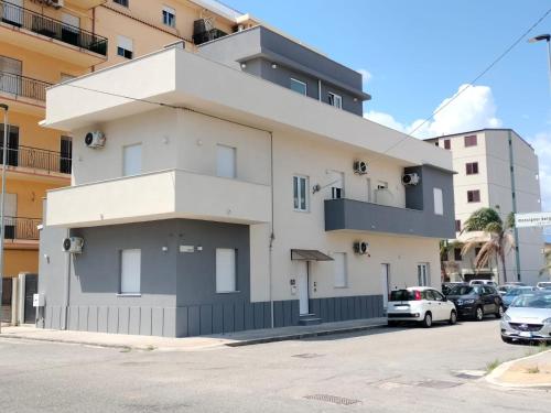 a white and gray building on the side of a street at Alcenide Aparthotel in Villa San Giovanni