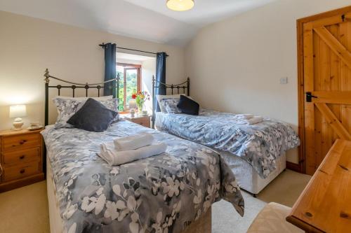 a bedroom with two beds and a wooden door at 3 Bed in Bodmin oc-ltbra in Cardinham