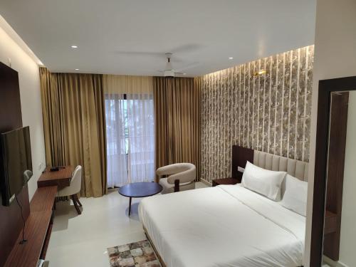 ein Hotelzimmer mit einem großen Bett und einem Schreibtisch in der Unterkunft Tidal Crest in Kundapura