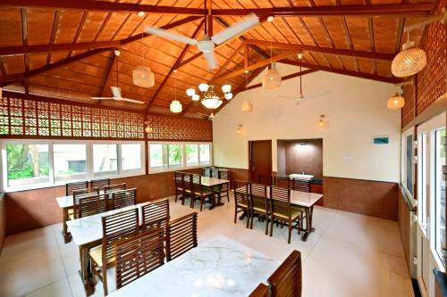 ein Esszimmer mit Holzdecke, Tischen und Stühlen in der Unterkunft Tidal Crest in Kundapura