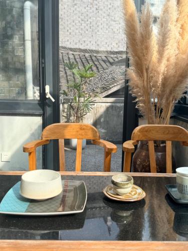 zwei Stühle und ein Tisch mit Tellern und Tassen. in der Unterkunft Interlude Inn, Boutique Art Retreat, Cultural Experience, Artisan Breakfast in Fenghuang