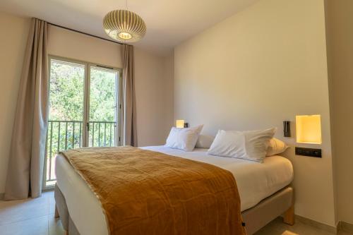 a bedroom with a bed with a large window at Résidence San Petru - 4 étoiles in Porto-Vecchio