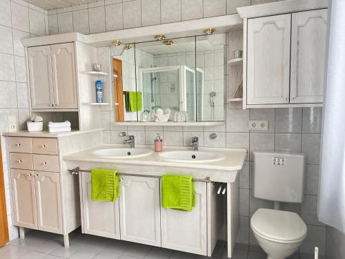 a white bathroom with two sinks and a toilet at Ferienwohnungen Irmengard in Bernau am Chiemsee