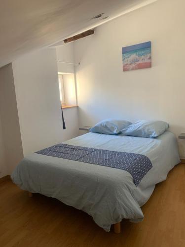 a bedroom with a bed with two pillows on it at Le bleu des toits in Lodève