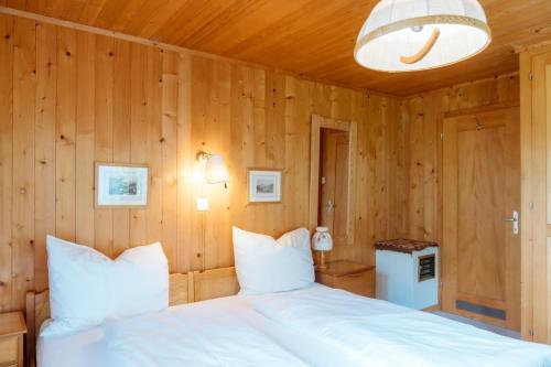 a bedroom with a large white bed with wooden walls at Chalet Engihalde in Amden