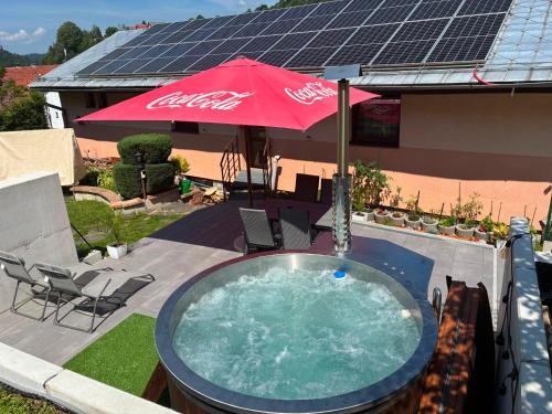 a hot tub with an umbrella next to a house at Penzion Ján in Habovka