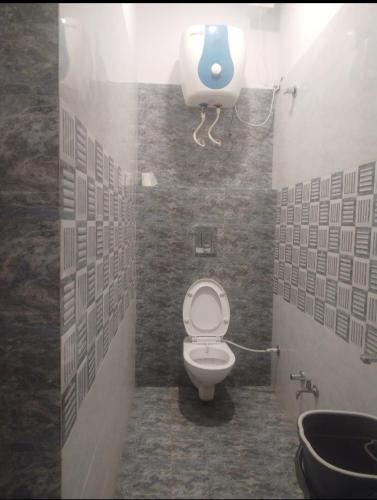 a bathroom with a toilet and a soap dispenser on the wall at HOTEL GILL TOWER (GRAND) in Hanumāngarh