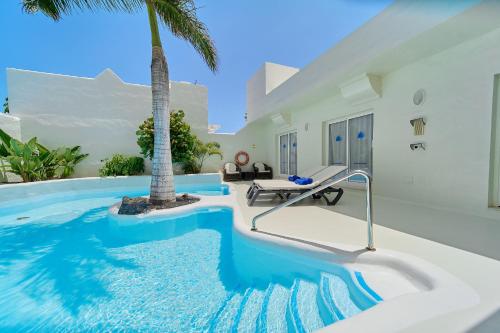 a swimming pool in a villa with a palm tree at KATIS Villas Fuerteventura in Corralejo