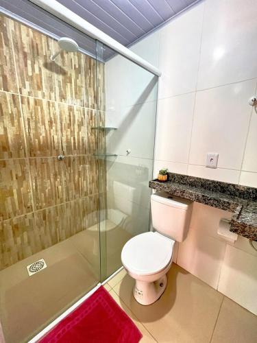 a bathroom with a toilet and a glass shower at Loft Azul - Pousada Vila Dondom in Luis Correia