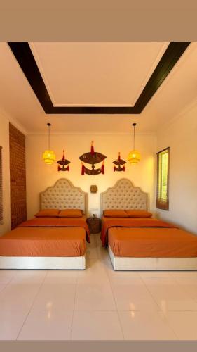 two beds in a bedroom with orange beds sidx sidx sidx at Bunohan Villa Roomstay in Tumpat