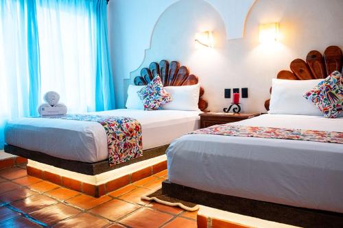 two beds in a room with blue walls at Hotel Posada Pablo de Tarso in San Patricio Melaque