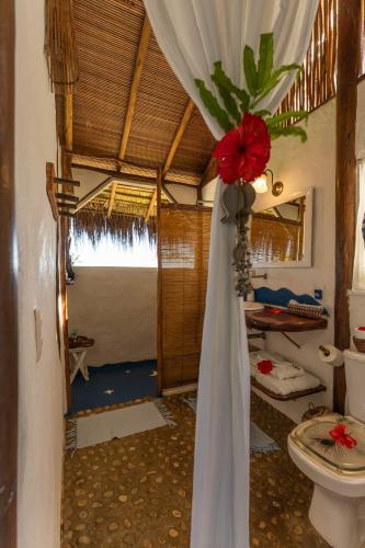 a bathroom with a curtain and a toilet in a room at Eco-Casa Bobô in Ilha de Boipeba
