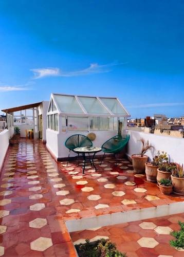 a patio with a table and benches on a roof at Dar Latigeo in Essaouira